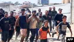 Banorët e Gazës duke e bartur një burrë të plagosur, i cili besohet se ka qenë duke pritur për ndihma. 