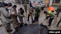 Робітники збирають мазут на узбережжі. Крим, грудень 2024 року. (Скриншот із відео)