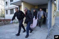 Люди виносять поранених внаслідок російського удару по Харкову. 18 квітня 2025 року