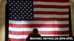 Egy szavazó megáll egy pillanatra az Egyesült Államok nemzeti lobogója előtt, mielőtt leadná a szavazatát egy hillsboroi szavazóhelységben, Virginia államban 2020. november 3-án.