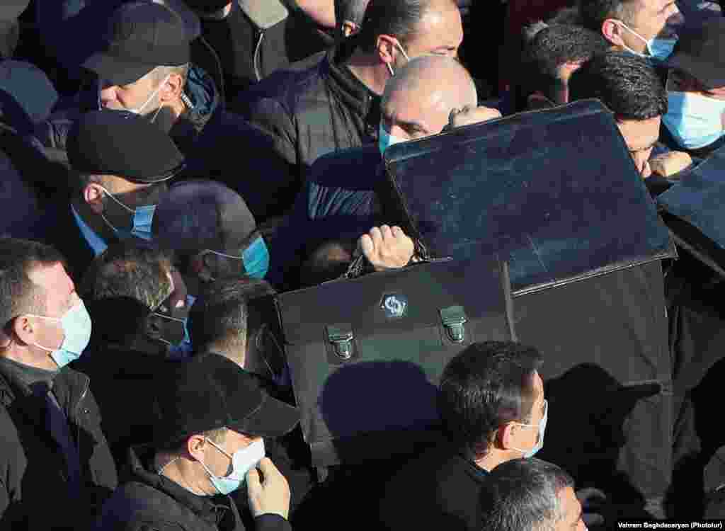 Телохранители го чуваат ерменскиот премиер Никол Пашинијан додека влегува на гробиштата во Јераблур на 19 декември.