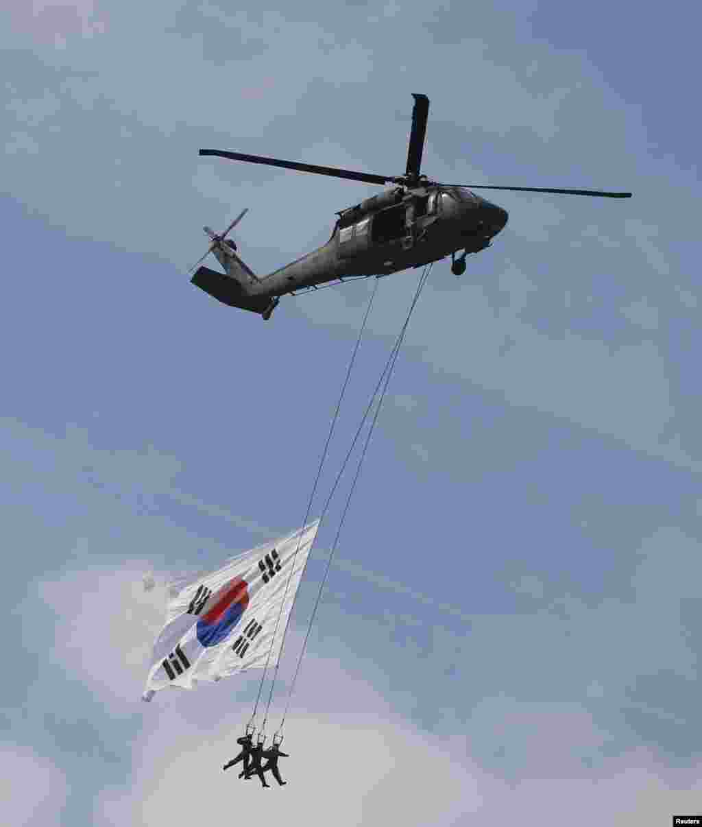Военнослужащие сил специального назначения, спущенные на тросах с вертолетов во время авиашоу на военном аэродроме к югу от Сеула
