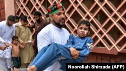 A volunteer carries an injured boy to a hospital, following multiple bomb blasts in Jalalabad on August 19.