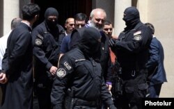 Ofițeri ai Serviciului Național de Securitate în timp ce îl arestează pe arhiepiscopul Bagrat Galstanian în capitala Armeniei, Erevan, pe 25 iunie 2025.