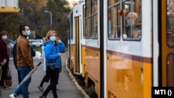 A koronavírus járvány miatt védőálarcot viselő utasok egy budapesti villamosmegállóban 2020. október 31-én.