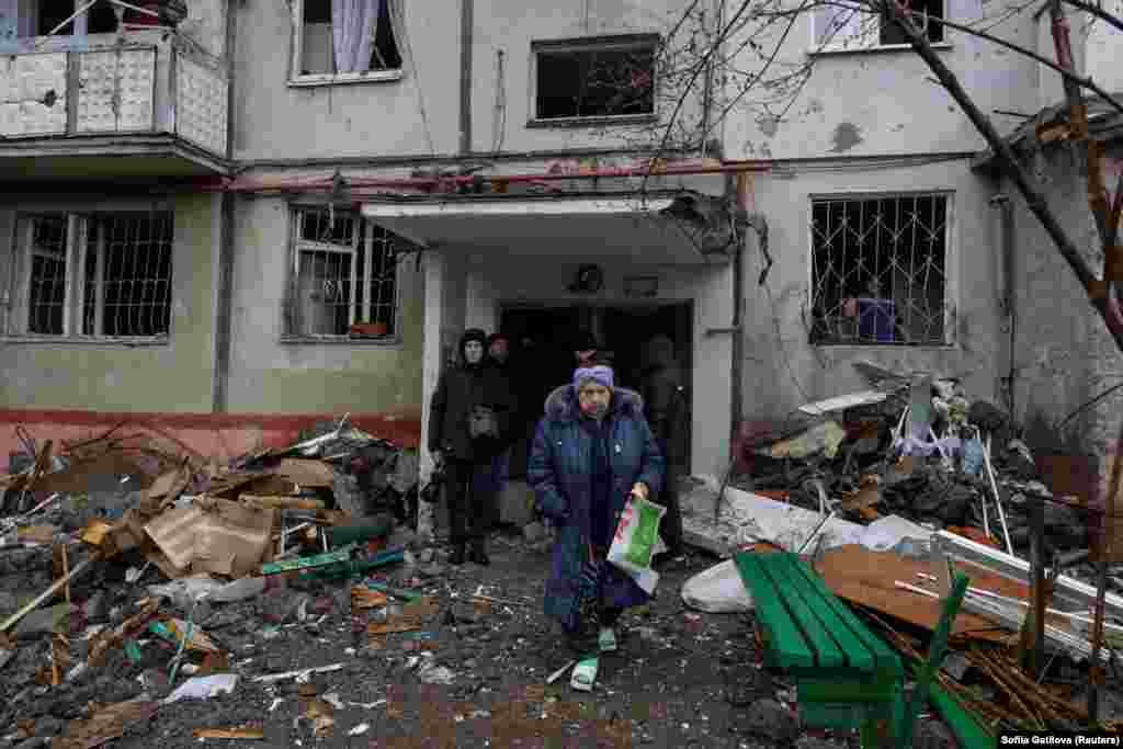 Жителі поряд з пошкодженим обстрілом будинком у Полтаві