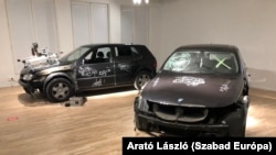 Karcoló gép egy autóroncson egy brüsszeli kiállításon, 2021 tavaszán