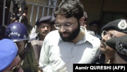 In this file taken on March 29, 2002, Pakistani police surround handcuffed Omar Sheikh as he comes out of a court in Pakistan's port city of Karachi.