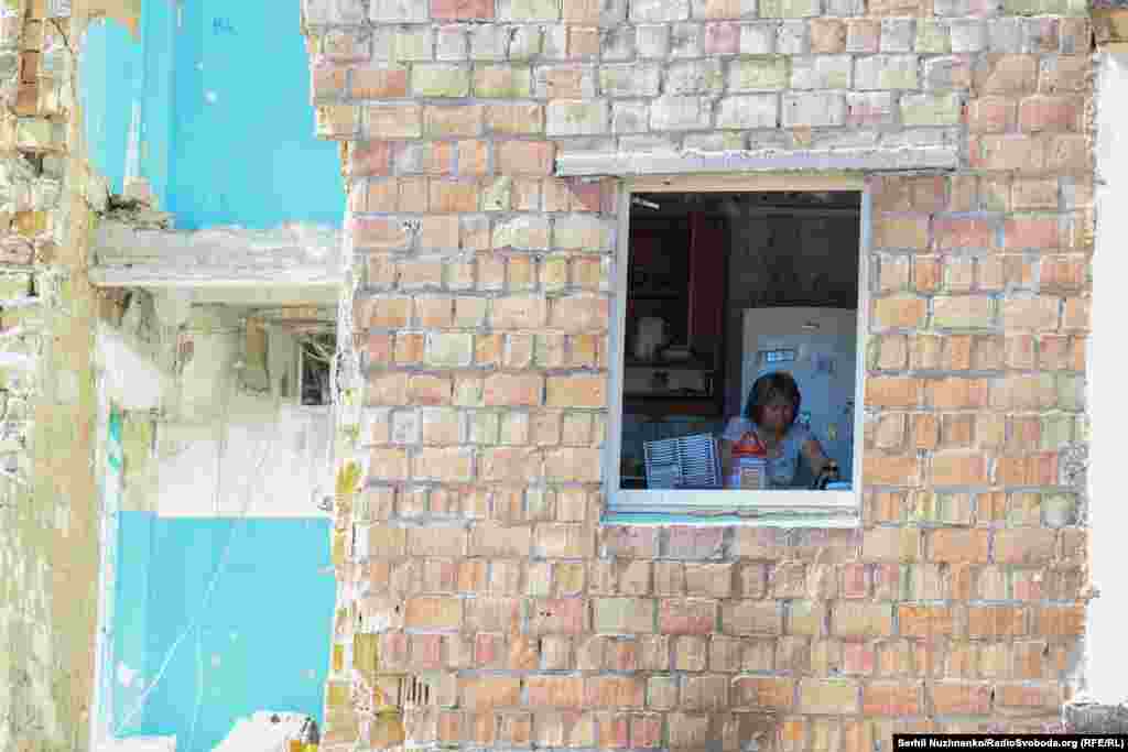 Жінка на кухні без вікна у своїй квартирі у вцілілій частині п'ятиповерхівки, в яку влучила російська ракета у ніч проти 28 серпня 2025 року під час масованої атаки сил РФ на Київ. Фото від 29 серпня 2025 року