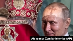 Crucea de pe mitra patriarhul Kiril aruncă o umbră pe fruntea lui Vladimir Putin în catedrala din Moscova, 28 aprilie, 2019