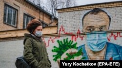 O tânără trecând pe lângă o pictură murală dedicată SARS-CoV-2. Moscova, 19 noiembrie 2020