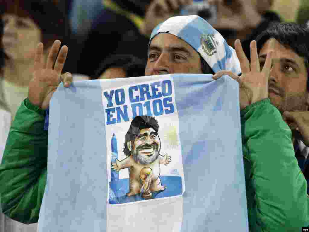 არგენტინის ნაკრების გულშემატკივარს უჭირავს დროშა წარწერით: „მე მწამს ღმერთის“. „ღმერთი“ დიეგო მარადონაა. - სამხრეთ აფრიკის სტადიონებზე გრძელდება მსოფლიო ჩემპიონატი ფეხბურთში. ფიფას თასისთვის ბრძოლა ძალას იკრებს. გამარჯვებული 11 ივლისს გამოვლინდება. 