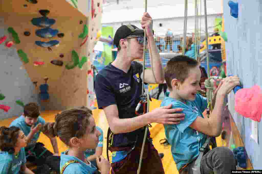 Instructorul Florin Selejan ajută un copil cu deficiență de vedere să se cațere, la Centrul Climb Again din București.