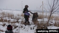 Чек арадагы көмүскө жолдон өтүп жаткан жарандар.