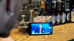 A bartender watches a live stream of Russian President Vladimir Putin's annual televised call-in show in a bar in Moscow on June 30.