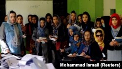 Election observers watch the counting of ballots during parliamentary elections at a polling station in Kabul on October 21.