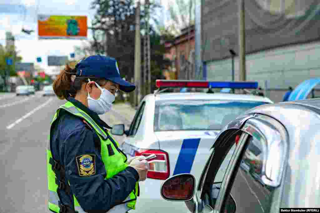 Жарандарды текшерип жаткан милиция кызматкери.