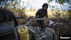 Un militar ucrainean cărând un proiectil de tanc, pe o poziție din apropierea liniei frontului, în afara orașului Bahmut