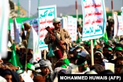 شبه‌نظامی حوثی روز سه‌شنبه در صنعا در کنار پرچم حوثی‌ها، با شعارها مرگ بر آمریکا و اسرائیل و شعار لعنت به یهودیان. حوثی‌ها از حمایت جمهوری اسلامی برخوردار هستند.