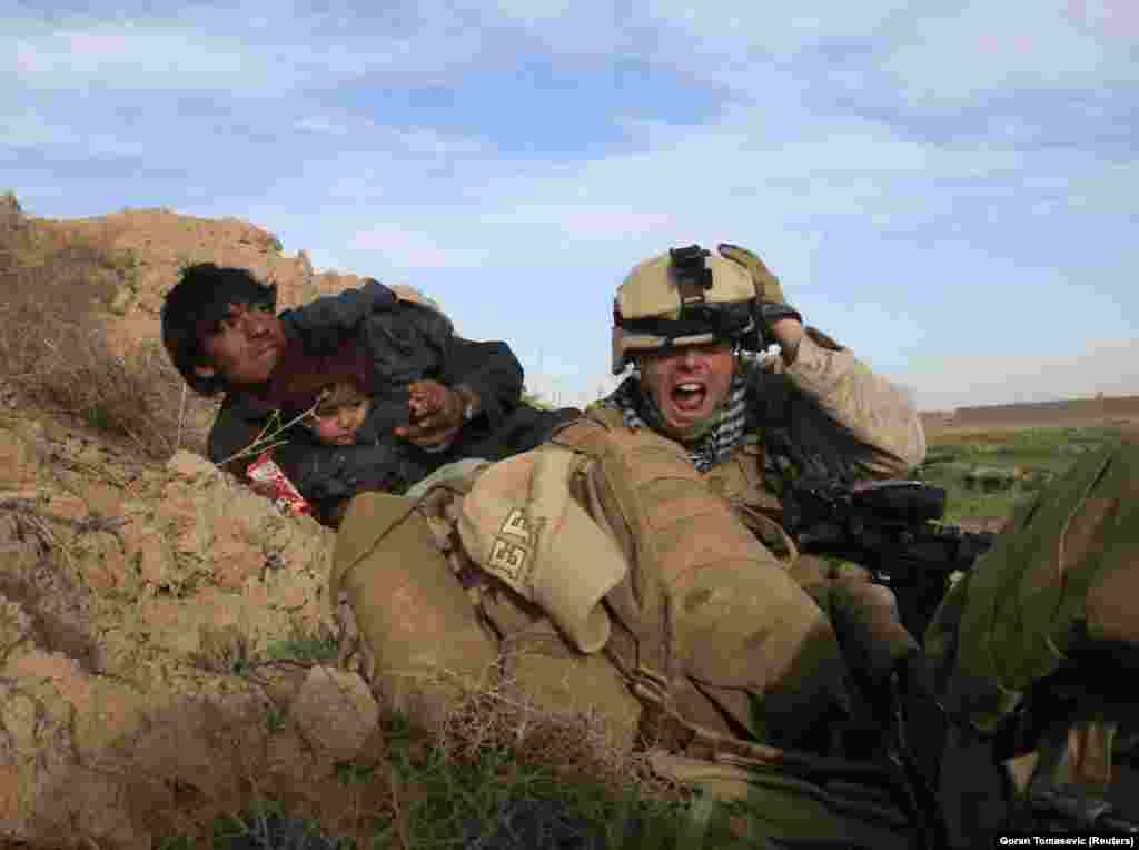 Un pușcaș marin american și doi civili afgani se ascund în timpul unui schimb de focuri cu militanții talibani în 2010.