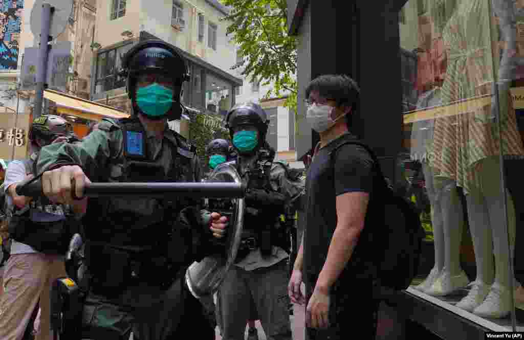 Poliția verifică pietonii care se îndreaptă spre centrul orașului, înaintea dezbaterilor din legislativul local, Hong Kong, 27 mai 2020.