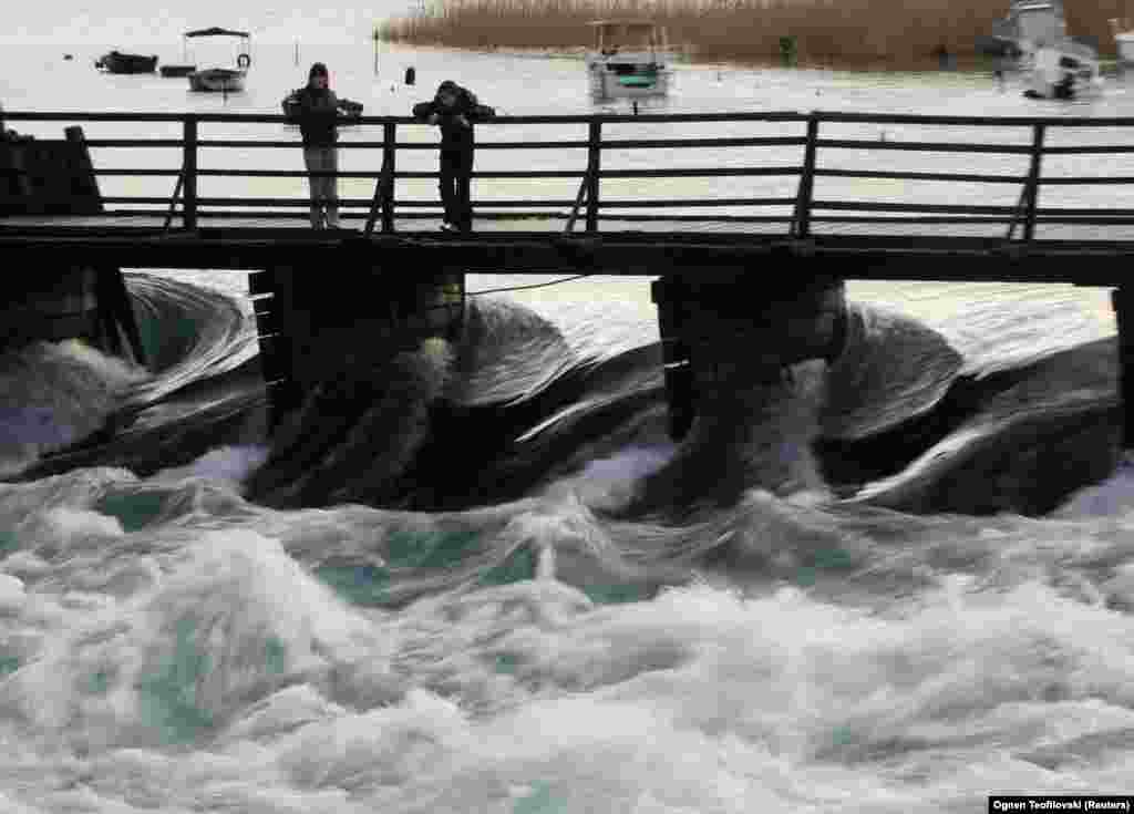 Vendësit në Strugë shikojnë ujin duke rrjedhur nga Liqeni i Ohrit në Lumin Drin. &nbsp; UNESCO-ja pritet të vendosë përfundimisht në qershor, nëse Ohri do të vendoset në listën e trashëgimive botërore në rrezik.