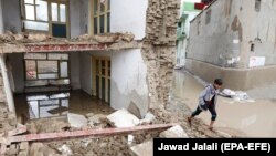 An Afghan boy passes by a collapsed house after flash flood in the west of Kabul on April 16.