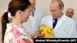 Владимир Путин в родильном доме в Калининграде берет новорожденного ребенка из рук его матери.