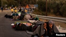 Egy pár ül az út szélén a leszboszi Moria tábor leégése után.