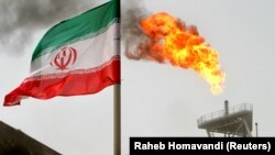A gas flare on an oil production platform in the Soroush oil fields is seen alongside an Iranian flag in the Gulf 