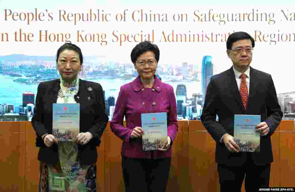 Голова адміністрації Гонконгу Керрі Лам (посередині), міністр юстиції регіону Тереза Ченґ (ліворуч) і міністр безпеки Джон Лі (праворуч) із виданнями нового закону про національну безпеку на пресконференції в Гонконгу 1 липня
