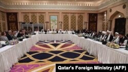 FILE: Qatari officials (C) take part in meeting between U.S. special envoy Zalmay Khalilzad (2nd-L), and the U.S. delegation, and Sher Mohammad Abbas Stanikzai (6th-R), and the Taliban delegation, in the Qatari capital Doha in February.