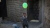 AFGANISTAN -- An Afghan internally displaced boy poses for a photograph as he holds a balloon near to a temporary shelter at an Internally Displaced Persons (IDPs) camp on the outskirts of Kabul, January 19, 2021