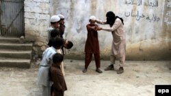 An unidentified militant of Islamic State (IS) imparting light weapons training to children at an undisclosed location in the Kunar province, eastern Afghanistan in July.