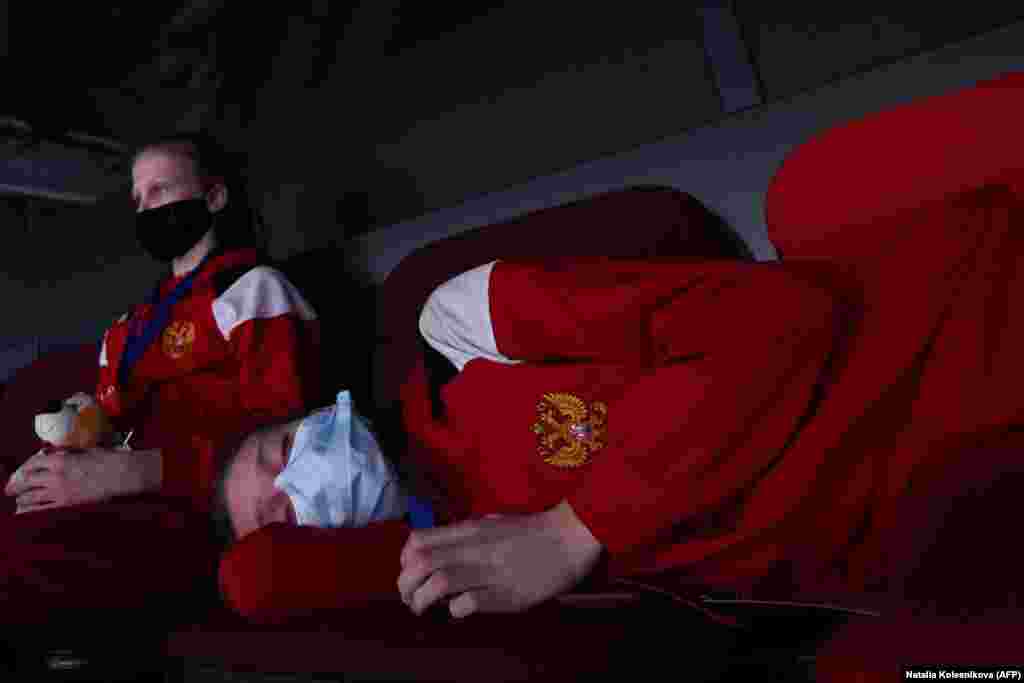 Një gjimnaste pushon, teksa një atlete tjetër shikon garën e parë të gjimnastikës ritmike për meshkuj, që u mbajt në Moskë. (AFP/Natalia Kolesnikova)