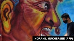 Egy gyalogos elhalad egy falfestmény mellett, amely tiszteleg a Covid–19 koronavírus terjedése ellen a frontvonalban küzdők előtt Mumbaiban 2021. február 28-án