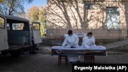 Medical staff prepare a coffin for the body of a patient who died of COVID-19 at the morgue of a hospital in Rivne, Ukraine.