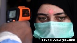 A railway staff checks temperature of a passenger as railway authorities resume the train operations, after the government eased coronavirus restrictive measures in Karachi on May 20. 