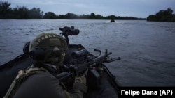 Украинские военные плывут на лодках по Днепру на передовой вблизи Херсона, 11 июня 2023 года