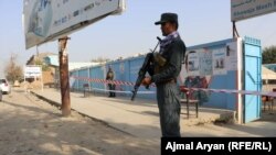 FILE: A police officer stands guard in front of a voting center in the northern province of Kunduz.