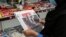 A woman browses the front page of the Iranian newspaper Sharq featuring the 2020 U.S. election results at a newsstand in Tehran on November 8, 2020.