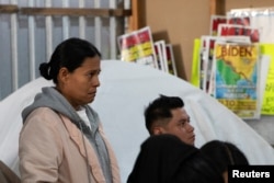 Тихуана (Мексика): мигранты из Латинской Америки, подавшие прошение в иммиграционную службу США, слушают инаугурационную речь Дональда Трампа 20 января 2025 г.