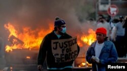 Një burrë mban në duar një pano ku shkruhet "Drejtësi për George". 