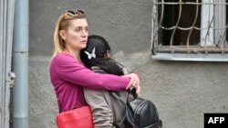 Helyiek egy rakétacsapás helyszínén Harkiv központjában 2024. április 7-én