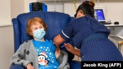 Медсестра вводить вакцину Pfizer/BioNtech Covid-19 Марґарет Кінан (л). Велика Британія, Ковентрі, 8 грудня 2020 року