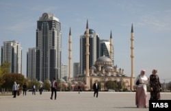 Люди на площі у Грозному. Височіють мінарети мечеті «Серце Чечні» та будівлі комплексу «Грозний Сіті». Під час двох російсько-чеченських воєн столиця Чечні була повністю зруйнована, а потім після приведення до влади прокремлівського Кадирова, Грозний відбудували за гроші Росії.