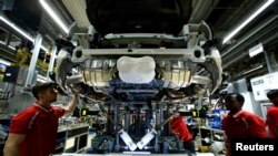 A Porsche német autógyár alkalmazottai egy sportautón dolgoznak a cég stuttgart-zuffenhauseni üzemében, Németországban, 2018. január 26-án.