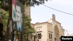 Nedavni izbori koje je organizovao sirijski režim ne mogu voditi bilo kakvim merama međunarodne normalizacije, rekao je portparol EU Peter Stano. Na slici: plakat Bašara al-Asada kod zgrade parlamenta u Damasku uoči predsedničkih izbora u Siriji, 18. april 2021.