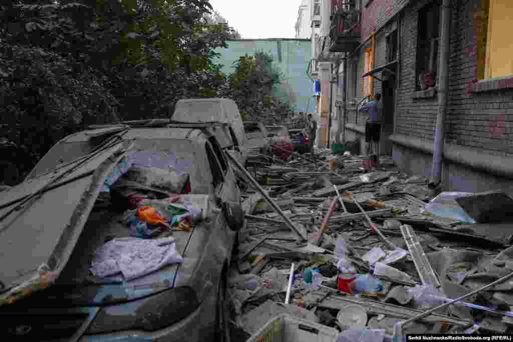 Прибудинкова територія, всіяна уламками, що летіли з уражених квартир. Припарковані автівки зазнали пошкоджень