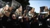 Women hold pictures of Iranian poet Simin Behbahani at her funeral in Tehran on August 22.
